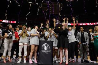 The Lady Rebels team holding up the Mountain West Conference trophy.